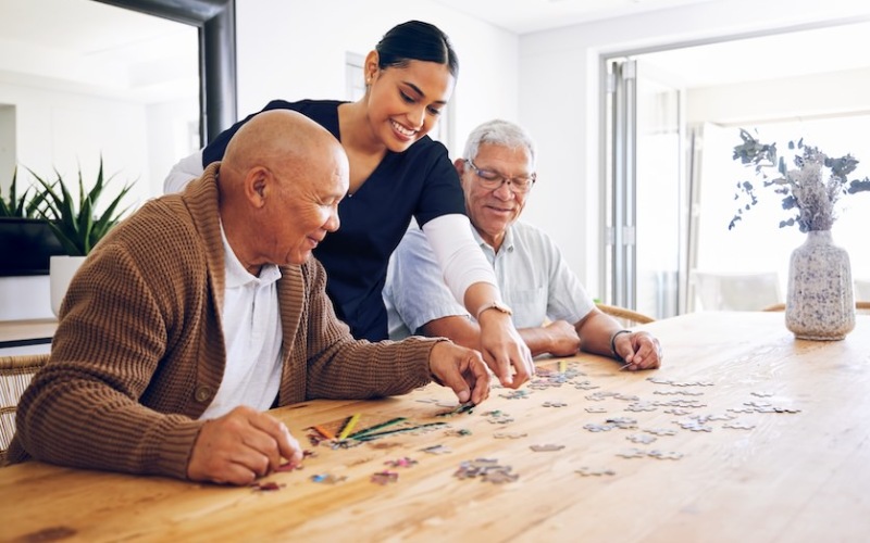 care member  and seniors enjoying a puzzle